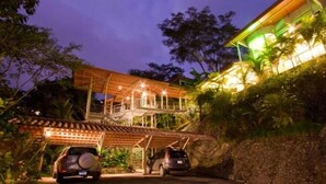 Un edificio de dos pisos con un espacio exterior cubierto y una escalera que conduce a un segundo nivel.