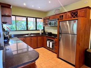 Una cocina con armarios de madera, un refrigerador de acero inoxidable, un microondas y un fregadero.