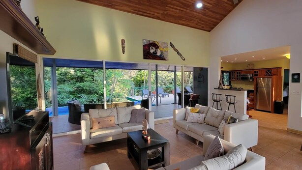 Un espacio habitable amplio con un gran ventanal, una cocina con electrodomésticos modernos y una zona de comedor con mesa y sillas.