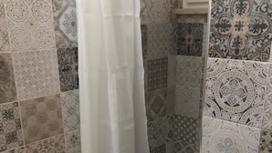 Une salle de bain avec un lavabo blanc, une douche avec un rideau blanc et des carreaux décoratifs sur les murs.