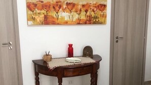 Une pièce avec une table en bois, un vase rouge et un tableau accroché au mur.