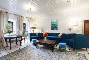 A living room with a blue sofa, a coffee table, a patterned rug, and a painting on the wall.