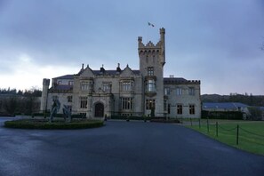 A large, historic building with a prominent tower and a statue in the foreground.