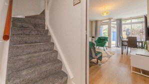 Eine Treppe führt zu einem Raum mit einem Essbereich, einem grünen Stuhl und einem Tisch.