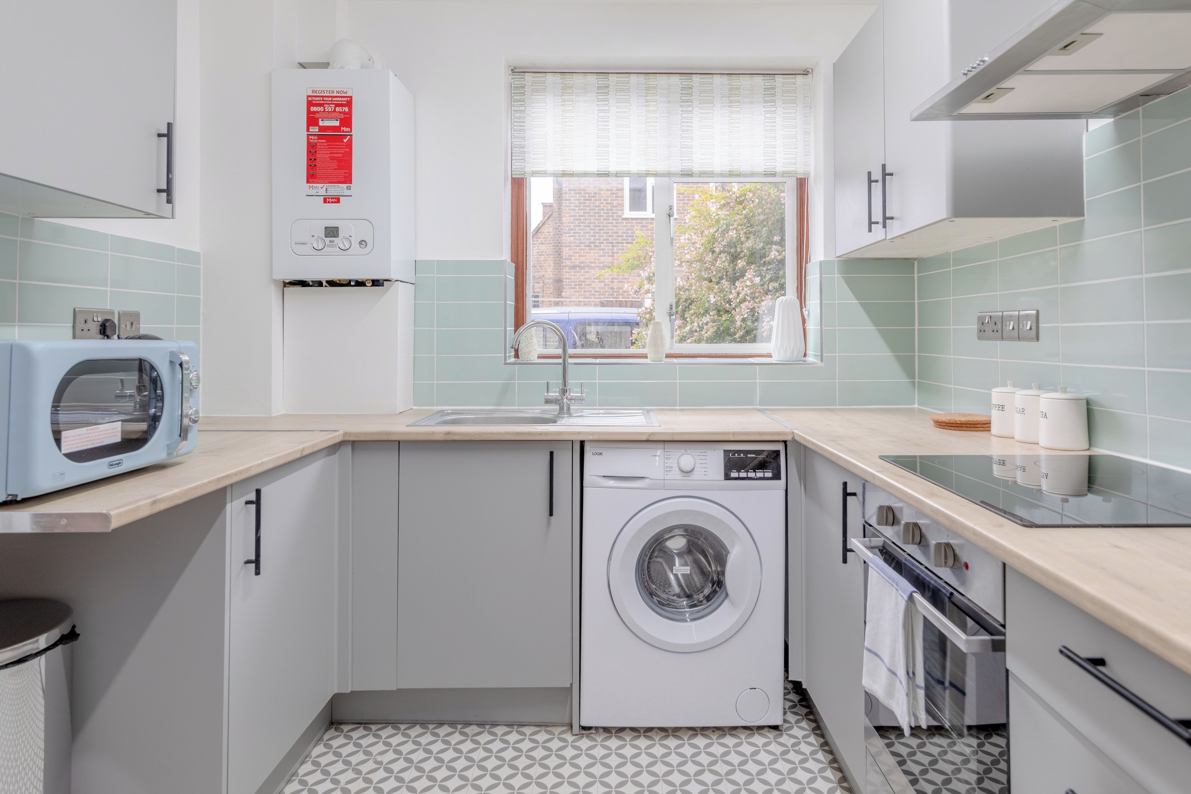 A compact kitchen with a washing machine, a microwave, and a sink.