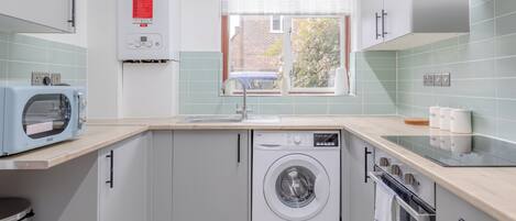 A compact kitchen with a washing machine, a microwave, and a sink.