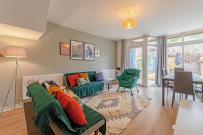 Un salon moderne avec un canapé, des fauteuils, une table à manger et une grande fenêtre.