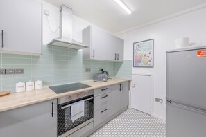 A modern kitchen with a built-in oven, a toaster, and a refrigerator. - Central 3BD House With Garden - 4min walk to Tube! (London)