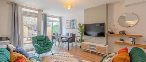 A modern living room with a sofa, a television, and a dining area.