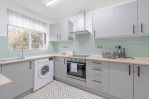 Une cuisine moderne équipée d’un lave-linge, d’un four et d’un grille-pain.