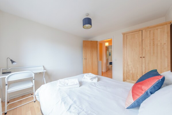 A bedroom with a bed, a desk, a chair, and a wardrobe.