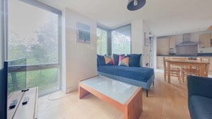 A modern living room with a sofa, coffee table, and large windows. - Spacious 2BDR Flat in the Heart of West London (London)