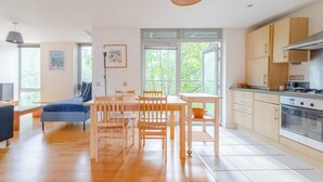 A modern kitchen with wooden cabinets, a dining table, and chairs. - Spacious 2BDR Flat in the Heart of West London (London)