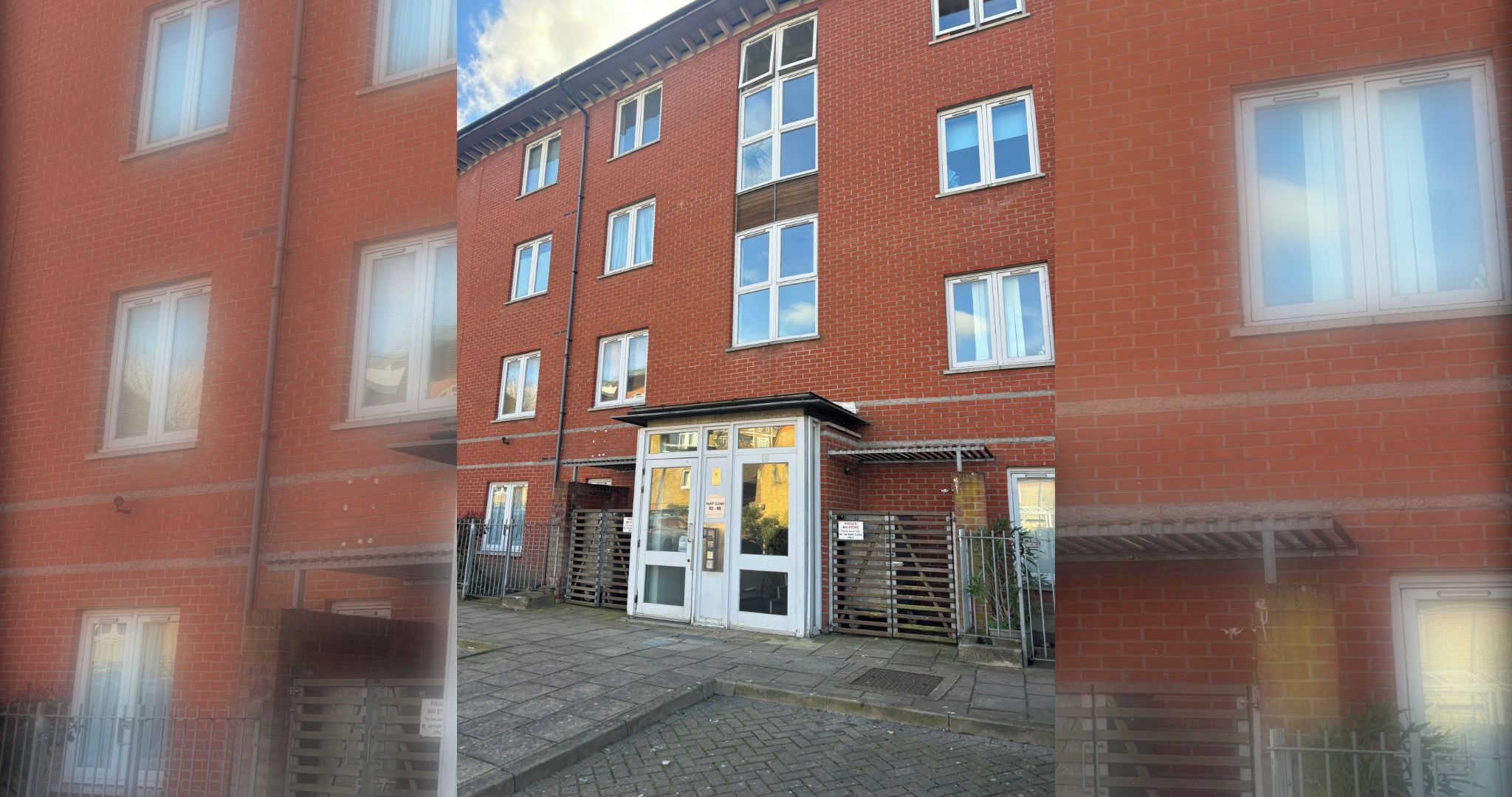 A red brick building with multiple windows and a gated entrance.