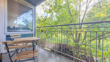 A balcony with a metal railing, a wooden bench, and a table.