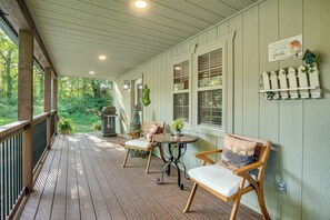 Relax on the covered porch with a seating area featuring two chairs and a table.
