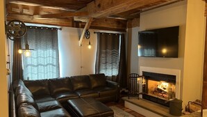 A cozy living room with a sectional sofa, a fireplace, and a flat-screen TV. - Okemo Condo on Bus Route in Center of Town (Ludlow)