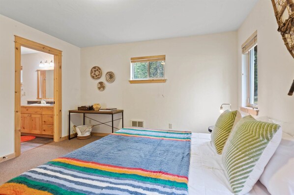 Un dormitorio con cama, ventana, escritorio y espejo.