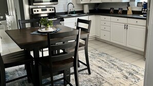 Una cocina moderna con armarios blancos, encimera negra y ventilador de techo.