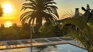 A swimming pool with a waterfall feature, surrounded by palm trees and a stone pathway. - TAJUYA SUITE (Los Llanos)