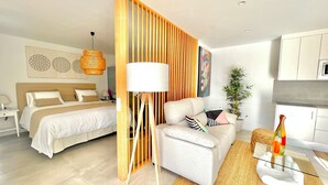 A modern hotel room with a bed, a sofa, a dining table, and a kitchen area. - TAJUYA SUITE (Los Llanos)