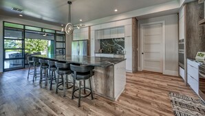 Een moderne keuken met een groot eiland, barkrukken en uitzicht op de omgeving.