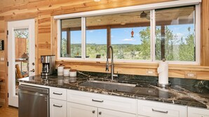 Una cocina con un ventanal grande, techo de madera y un lavamanos de acero inoxidable.