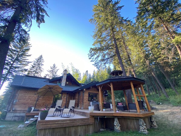 Une cabane dotée d’une terrasse, de meubles de jardin et d’une cheminée.