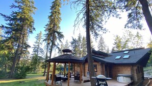 Eine Hütte mit einer Holzdiele, Sitzgelegenheiten im Freien und einem Grill.