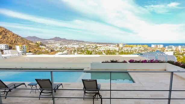 A rooftop pool area with lounge chairs and a view of a coastal cityscape. - CONDO LI BY TRVL2HM (Cabo San Lucas)