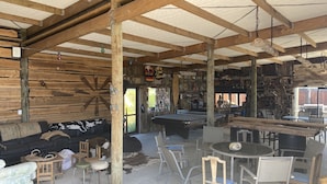 A rustic wooden interior with a pool table, bar area, and seating arrangements.