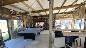 A rustic indoor space with a pool table, wooden chairs, and a cowhide rug.