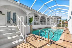 Una piscina coperta con tetto in vetro, ringhiere bianche e una scala che conduce a una porta con persiane.
