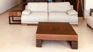 Un salon moderne avec un canapé blanc, une table basse en bois et une petite table d’appoint en bois.