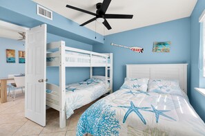 A room with bunk beds, a desk, and a ceiling fan.