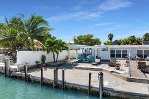 A waterfront property with a covered patio, outdoor seating, and a pool. - Adorable 2 Bedroom - Key Colony - Cabana Club - Dockage (Key Colony Beach)