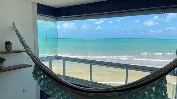 A hammock in a room with a view of the beach. - Bela Hospedagem-Apt frente mar no Bessa (João Pessoa)