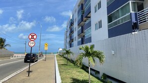 A modern building with balconies, a clear sky, and a speed limit sign of 30 km/h. - Bela Hospedagem-Apt frente mar no Bessa (João Pessoa)