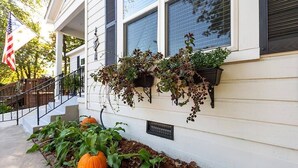 Uma casa com varanda, plantas em vasos e uma abóbora.