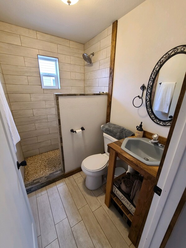 Un baño con ducha, inodoro, lavamanos y ventana.