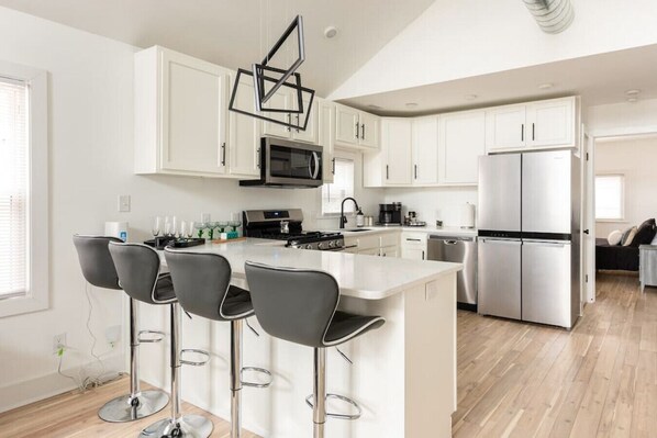 A modern kitchen with white cabinets, stainless steel appliances, and a central island with bar stools.