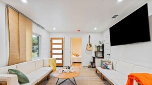 A modern living room with a sofa, a coffee table, and a TV. - Bali Inspired | Ping-Pong | Yoga | Massage | Bocce (Austin)
