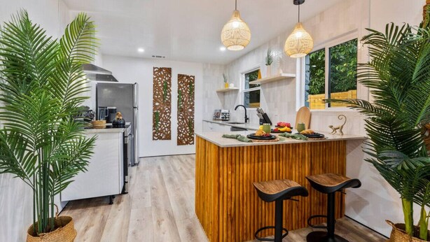 A modern kitchen with a wooden island, bar stools, and pendant lights. - Bali Inspired | Ping-Pong | Yoga | Massage | Bocce (Austin)