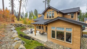 A wooden cabin with a patio area, stone retaining wall, and a view of the surrounding forest. - Family Friendly w/ Suncadia Pool Access (Cle Elum)