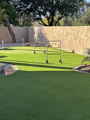 A well-maintained artificial grass area with a metal swing set and two flag markers. - Beautiful,Immaculate, Glendale home. (Glendale)