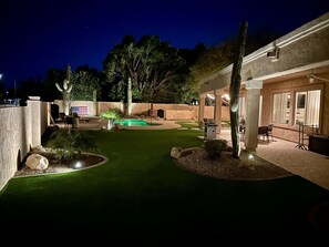 A well-lit backyard with a swimming pool, artificial grass, and cacti. - Beautiful,Immaculate, Glendale home. (Glendale)