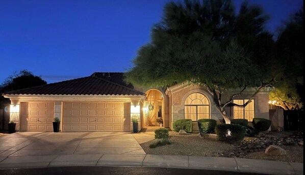 Enter through the arched entryway into this two-story house with a garage and beautifully maintained grounds.