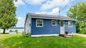 A single-story blue house with a white door and windows, a small porch with steps, and a mailbox.