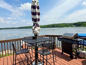 Eine Terrasse mit Tisch, Stühlen, einem Grill und einem Sonnenschirm.
