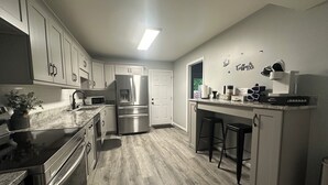A modern kitchen with stainless steel appliances, a marble countertop, and a coffee bar.